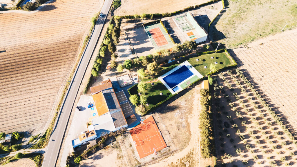 Vista aérea del club con instalaciones deportivas, piscina y zonas de recreo.
