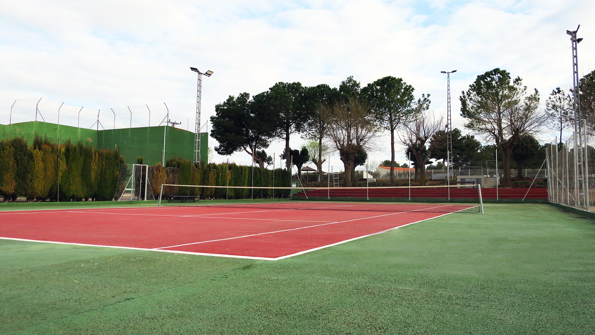 Cancha de tenis al aire libre rodeada de vegetación en el Club Deportivo y Cultural Las Tinajas
