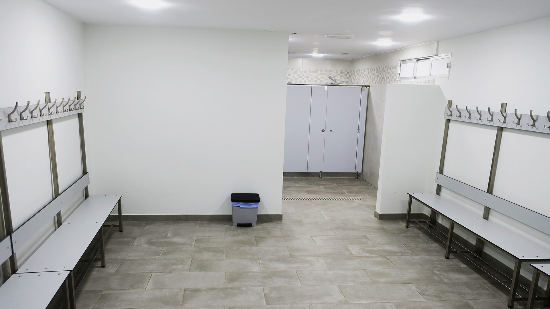 Interior del vestuario con bancos y percheros metálicos en el Club Las Tinajas